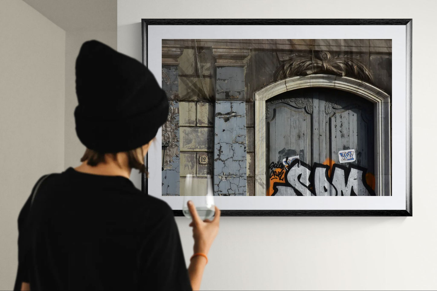 Person taking a photo of a framed artwork on a wall