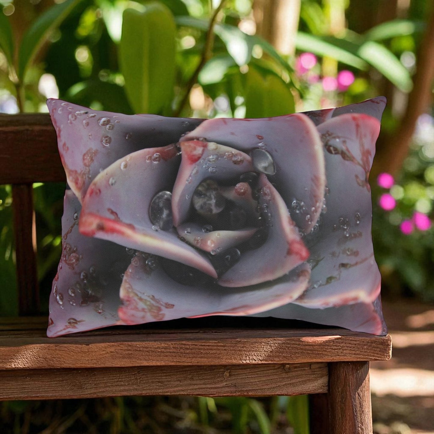 Decorative pillow with a succulent design on a wooden chair outdoors.
