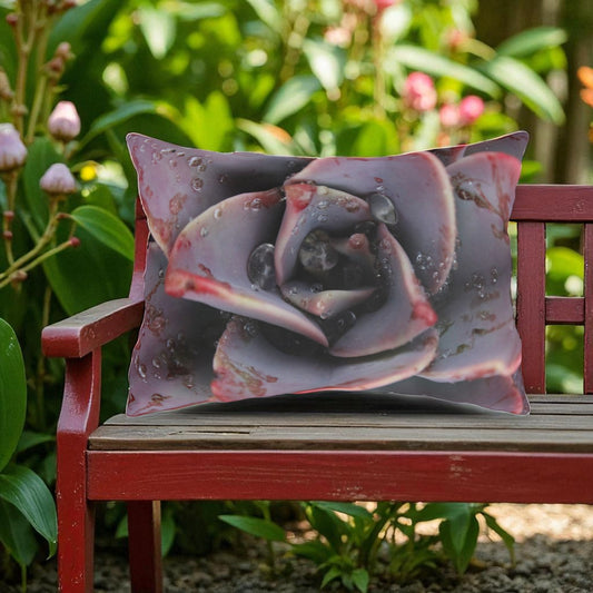 Decorative pillow with a succulent design on a red bench in a garden setting
