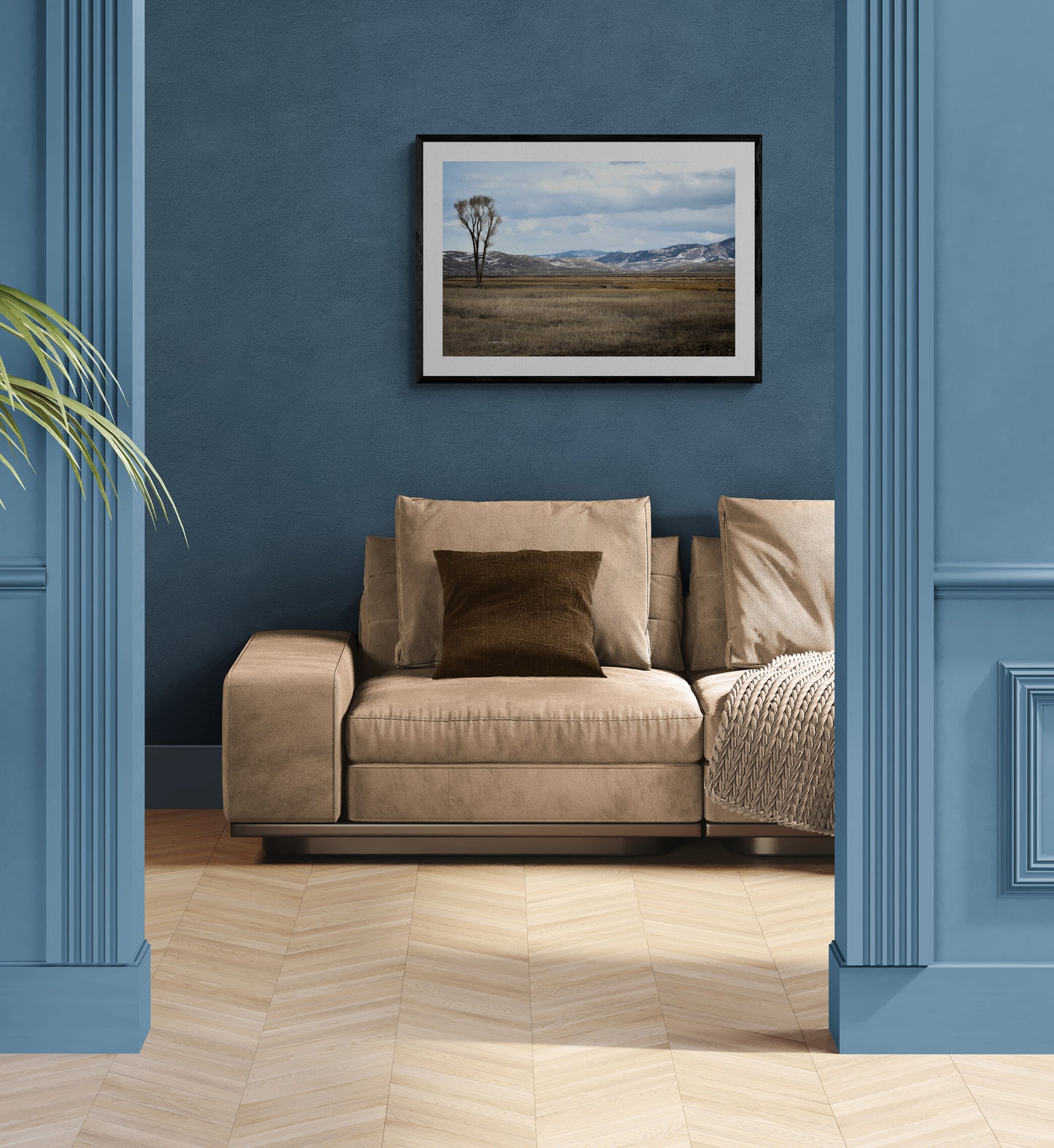 Beige sofa with cushions in a room with blue walls and a framed picture.
