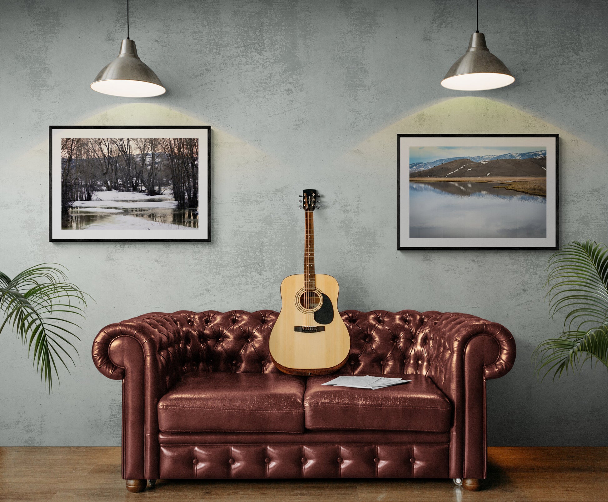 Acoustic guitar on a brown leather sofa with wall art and plants.