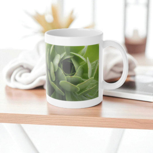 White mug with succulent plant design on a wooden surface