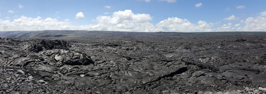 Panoramic photograph of the Kilauea lava field with rugged terrain and a blue sky in the background. Kilauea Lava Field Panoramic, Original Photograph by Kim A. Bailey