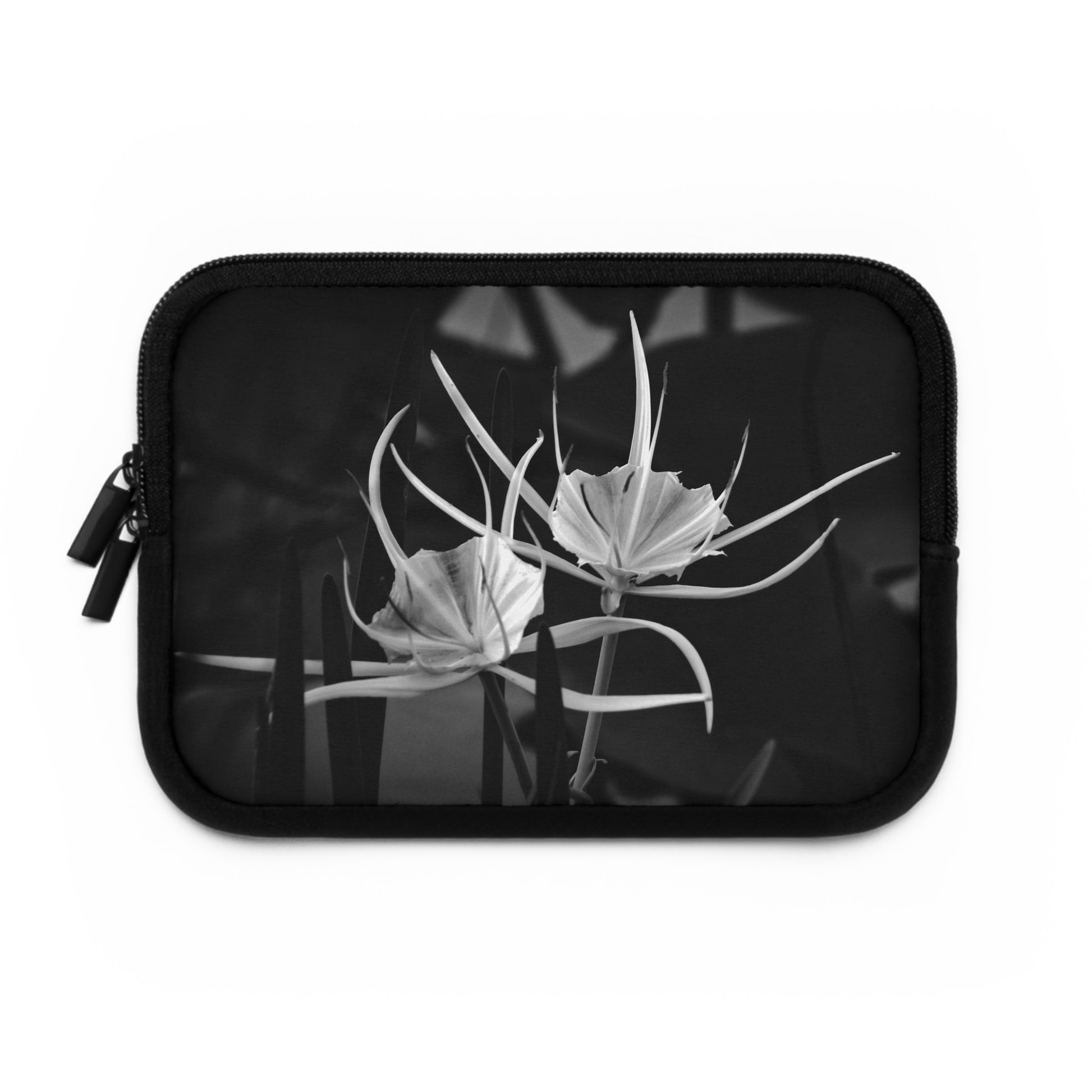 A black neoprene laptop or tablet sleeve featuring a white and black alligator lily photograph on the front.