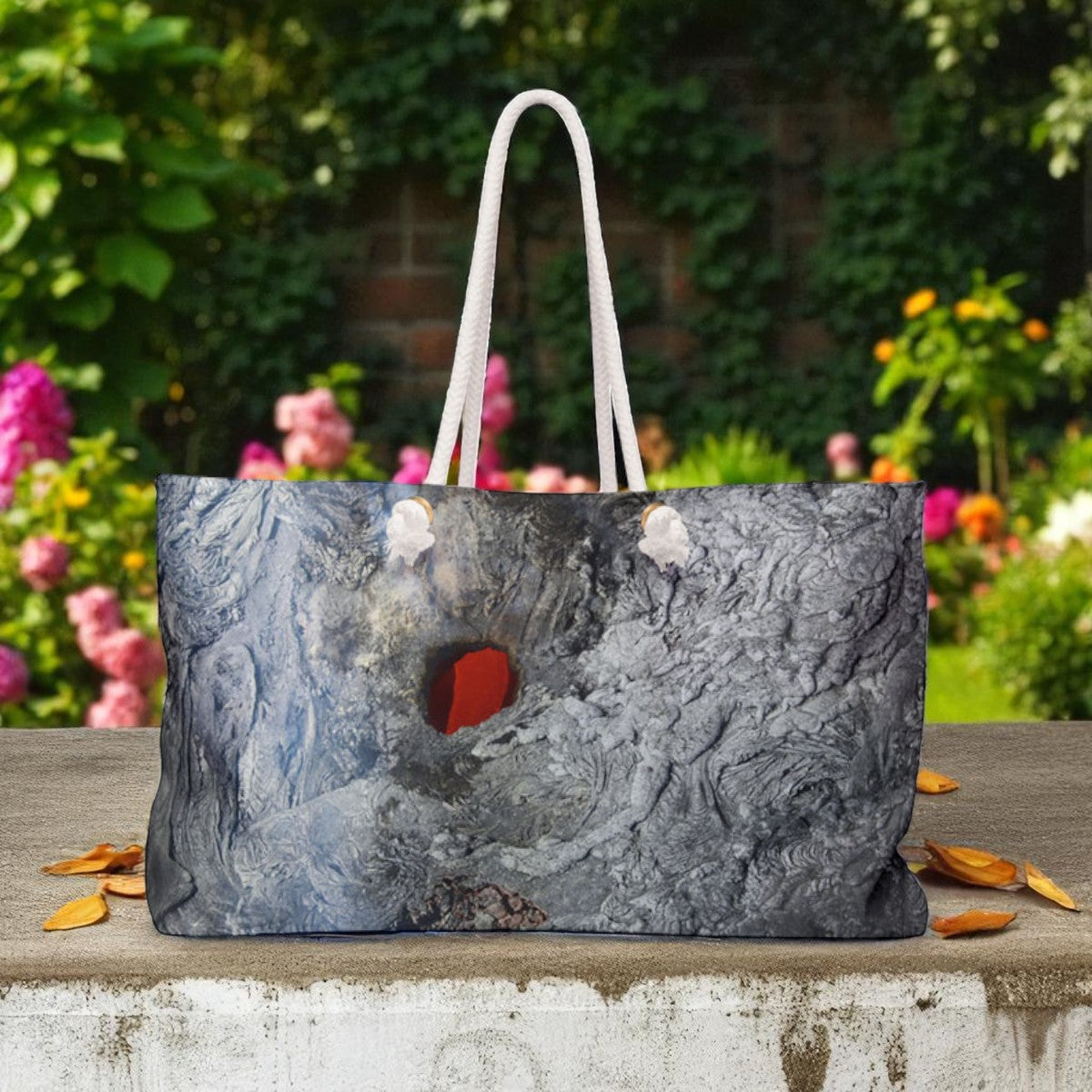 Marble-patterned tote bag with a red interior on a stone ledge with a garden background