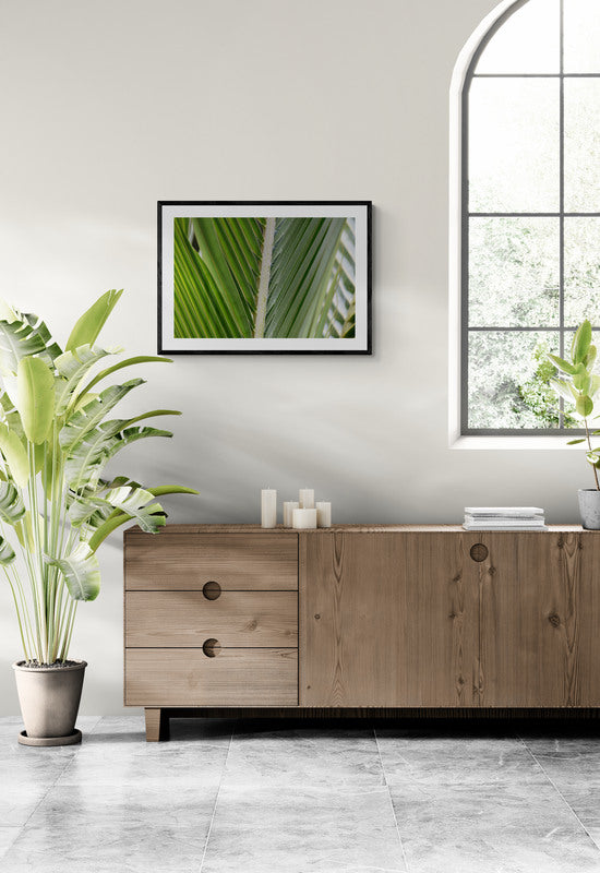 Modern interior with wooden sideboard, plants, and framed artwork on a light gray wall.