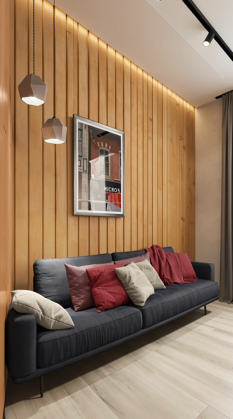 A modern living room corner featuring a dark gray fabric sofa with red and beige throw pillows, set against a warm wood-paneled wall with built-in LED lighting and a framed picture.
