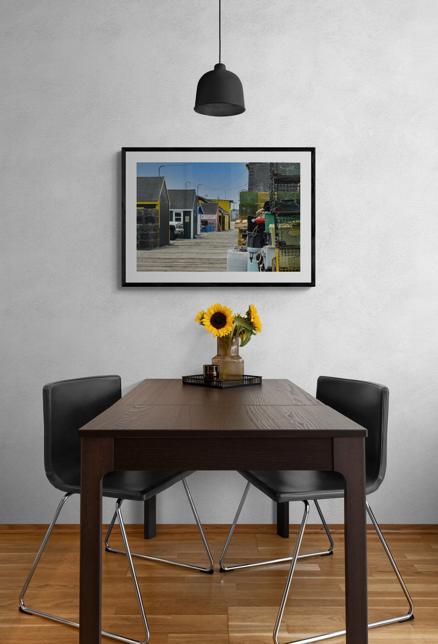 Dining room with a table, chairs, and a vase of sunflowers against a wall with a framed picture.