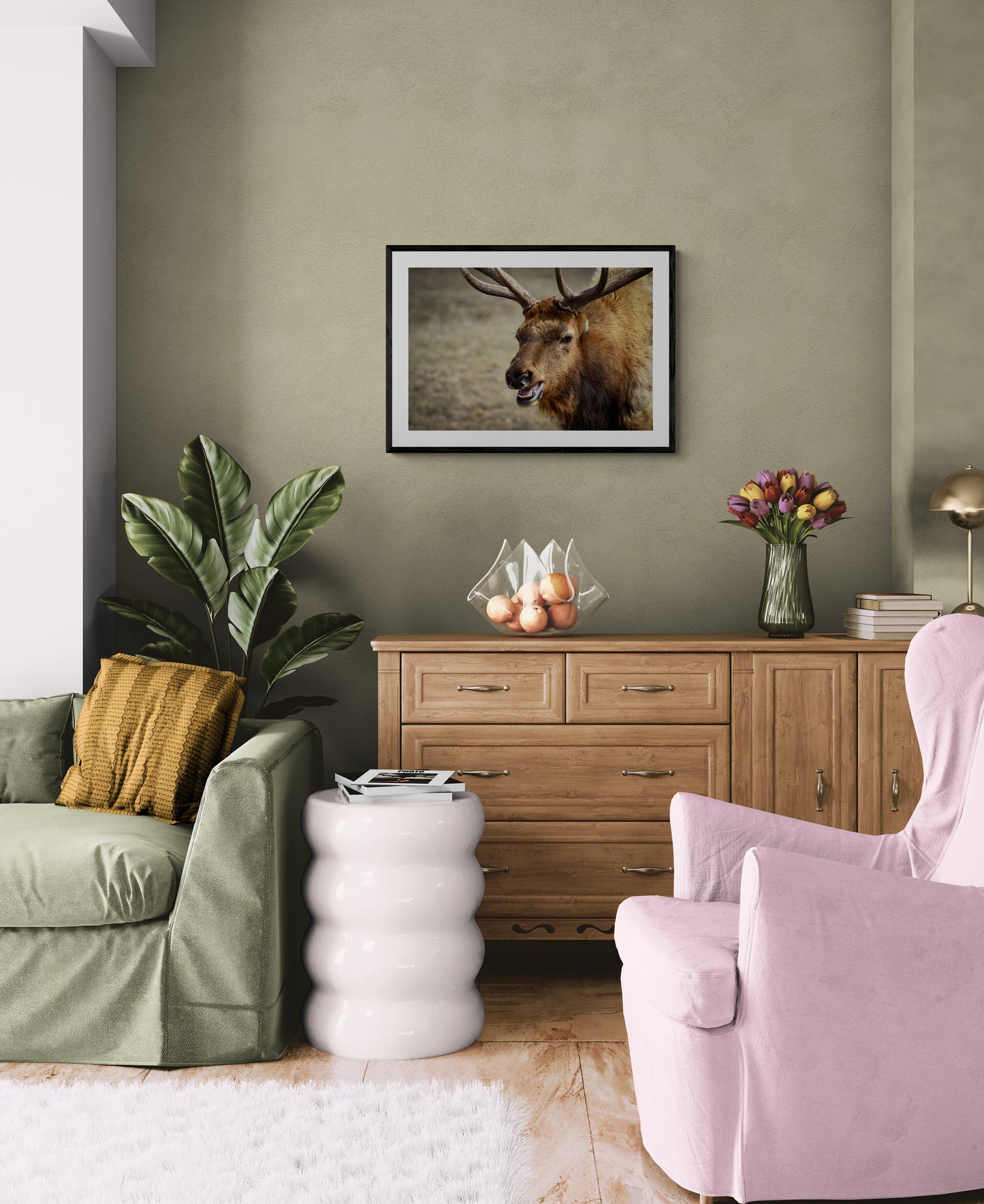 Living room with green sofa, pink armchair, wooden cabinet, and deer artwork on wall.