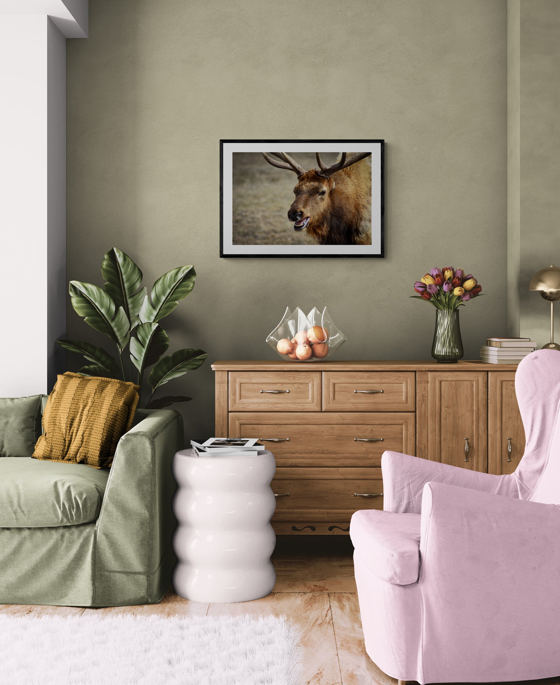 Living room with green sofa, pink armchair, wooden cabinet, and deer artwork on wall.