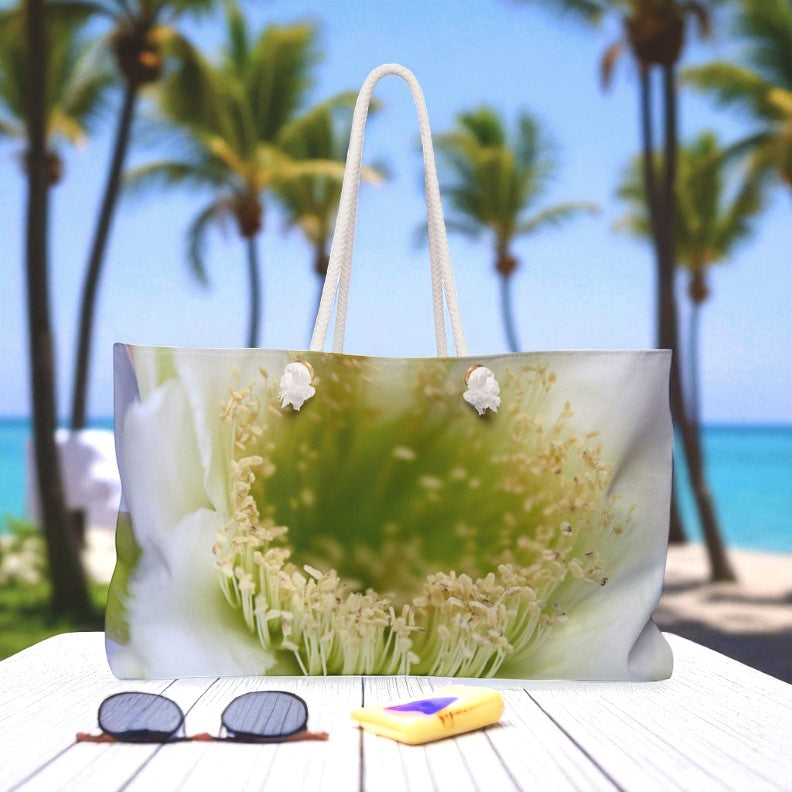 Tote bag with a floral design on a table with sunglasses and a book, palm trees and beach in the background