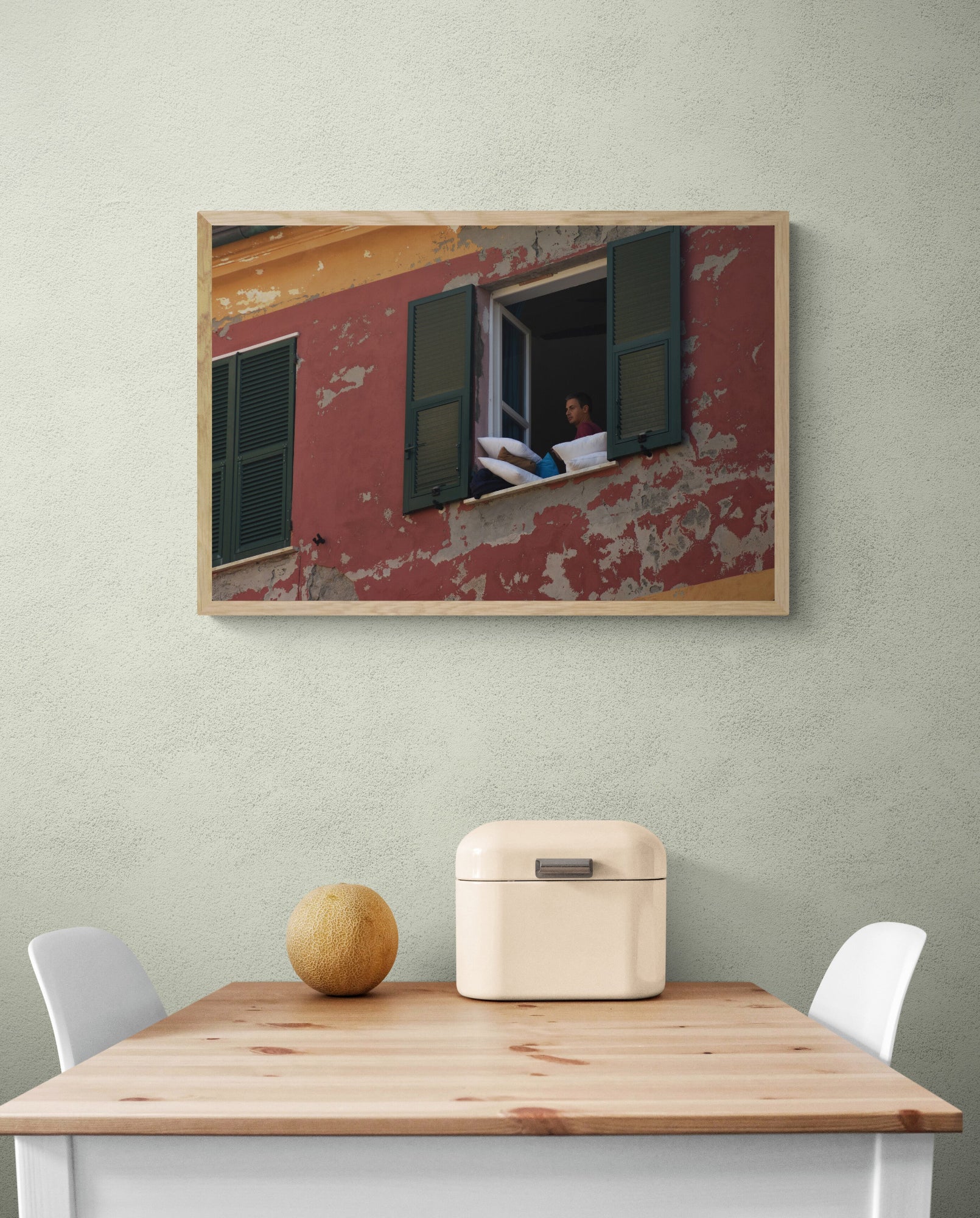 Framed artwork of a building with a window on a wall above a wooden table. Open_Window_Original_Photograph_by_Kim_A._Bailey