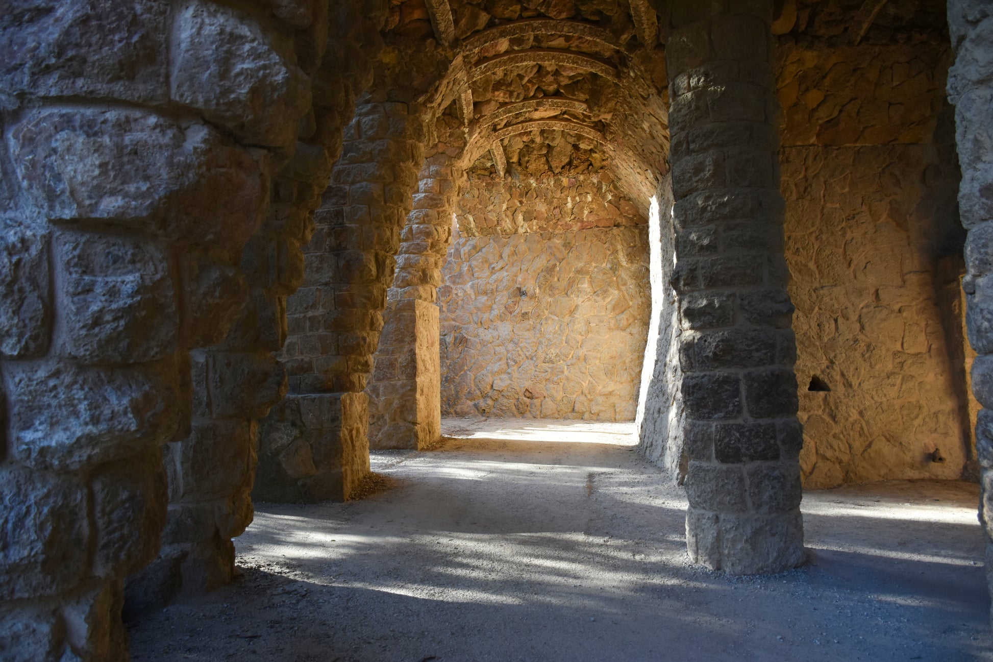 Stone archway with sunlight filtering through, creating a warm and historic atmosphere.