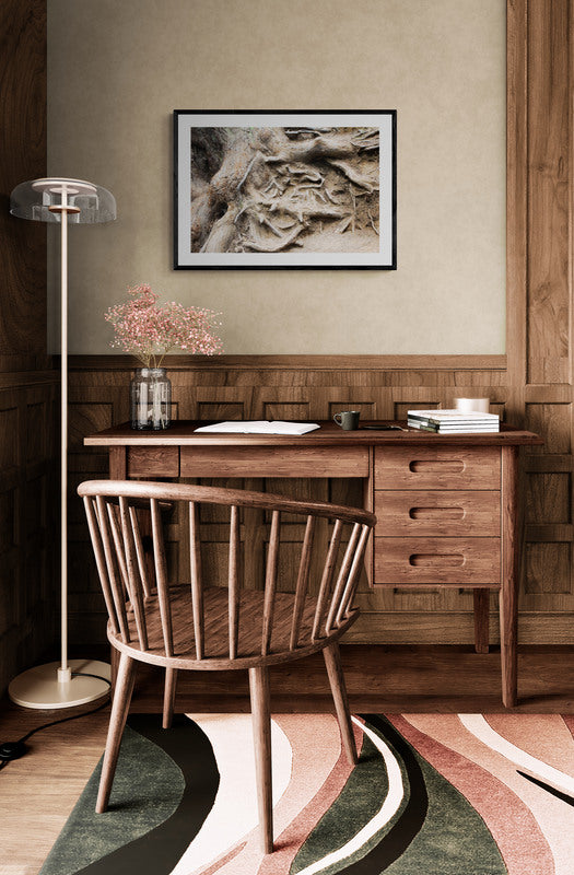 Wooden desk with chair in a room with a framed picture on the wall.