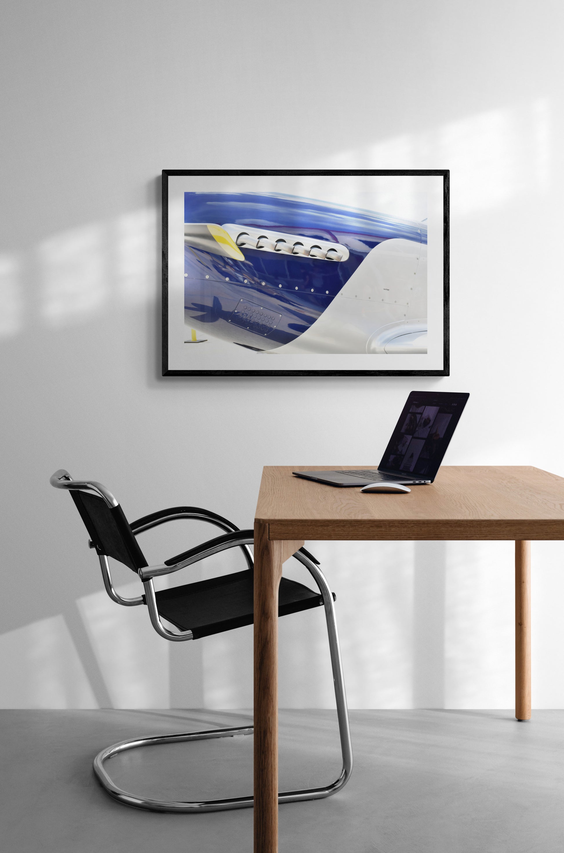 Modern office setup with a desk, chair, and framed artwork on a wall.