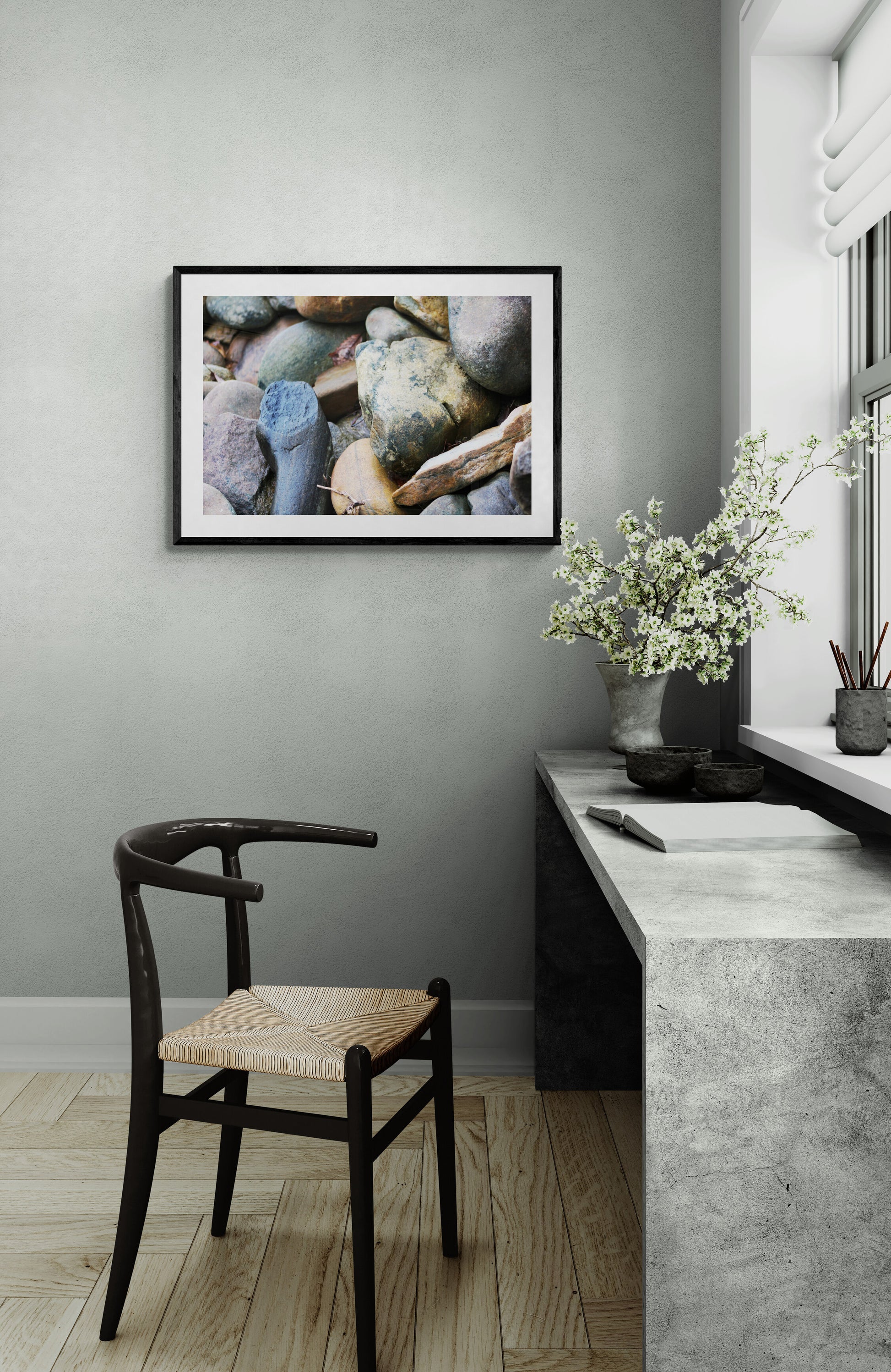 Modern interior with a framed picture of rocks on a gray wall, a wooden chair, and a vase with flowers on a windowsill.
