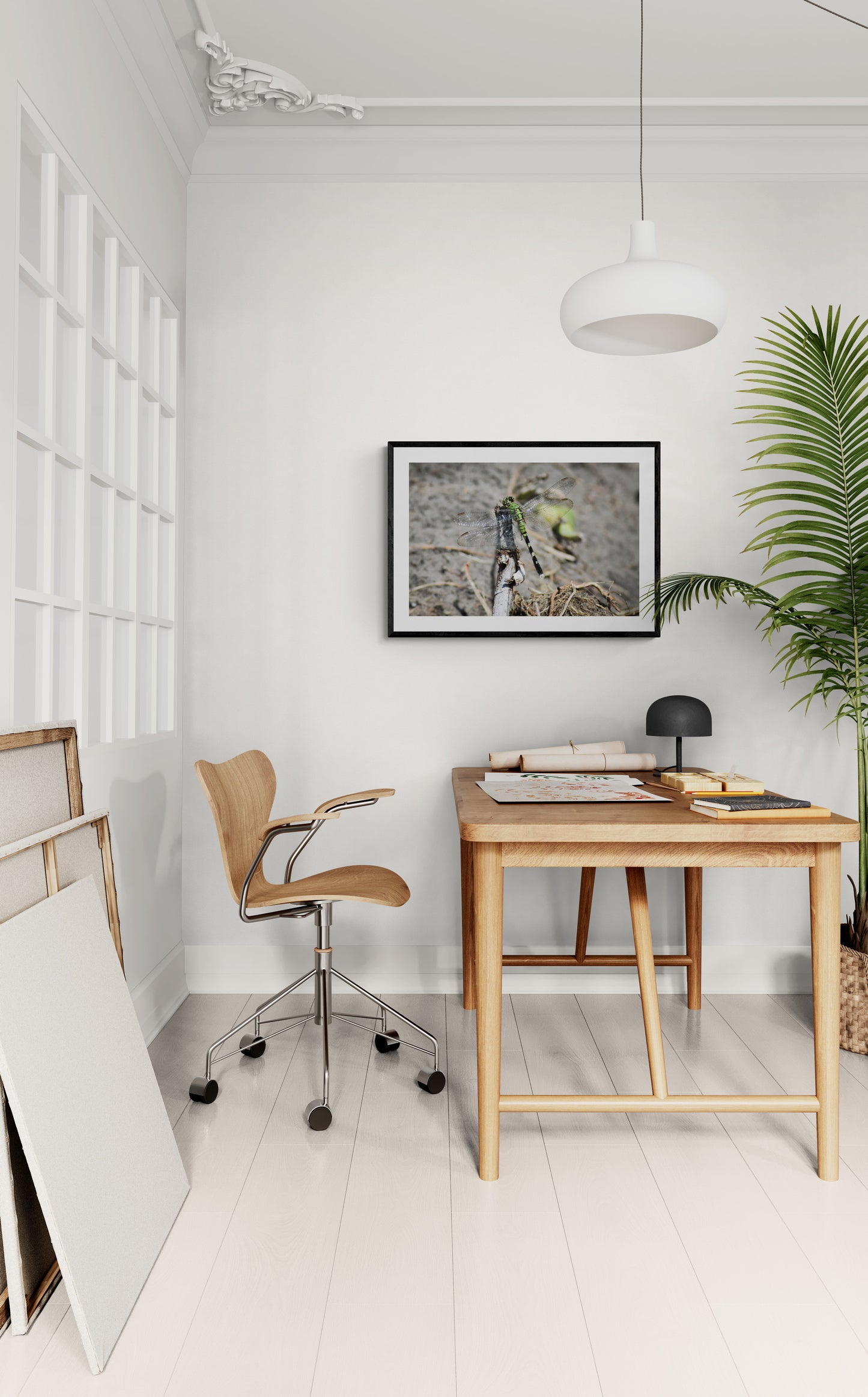 Home office with wooden desk, chair, and framed picture on white wall.
