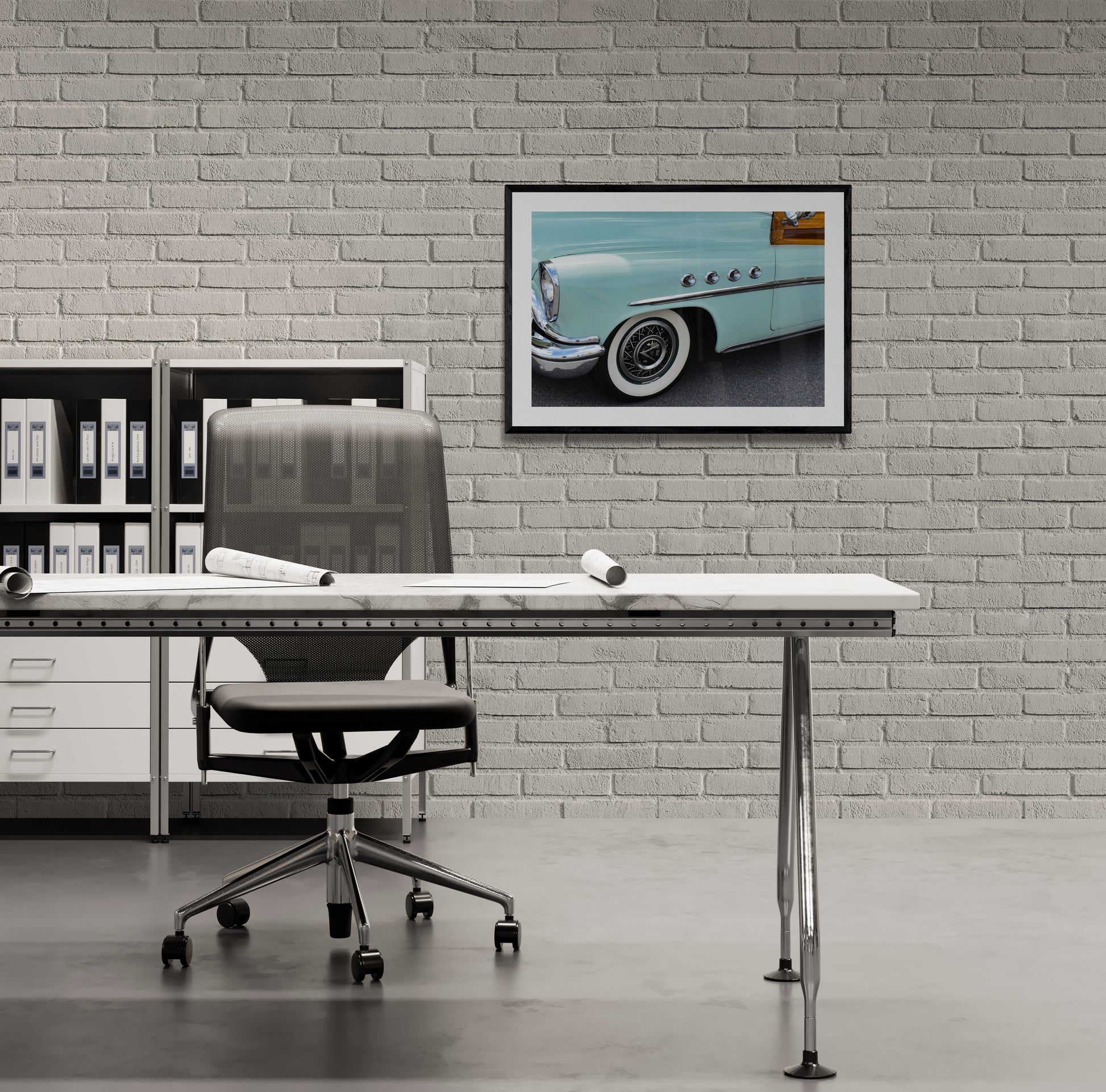 Framed photograph of a classic car on a brick wall above a desk.