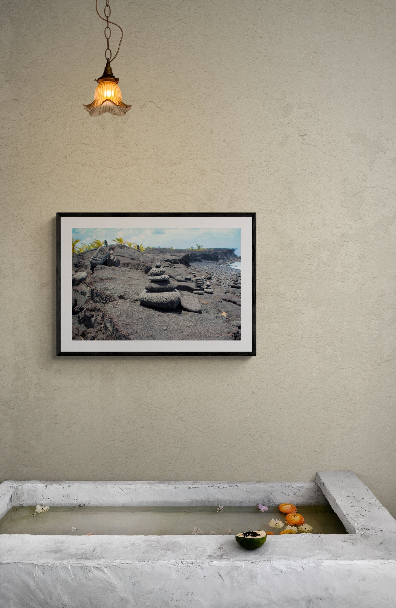 Framed photograph of a rocky landscape on a wall above a stone basin.