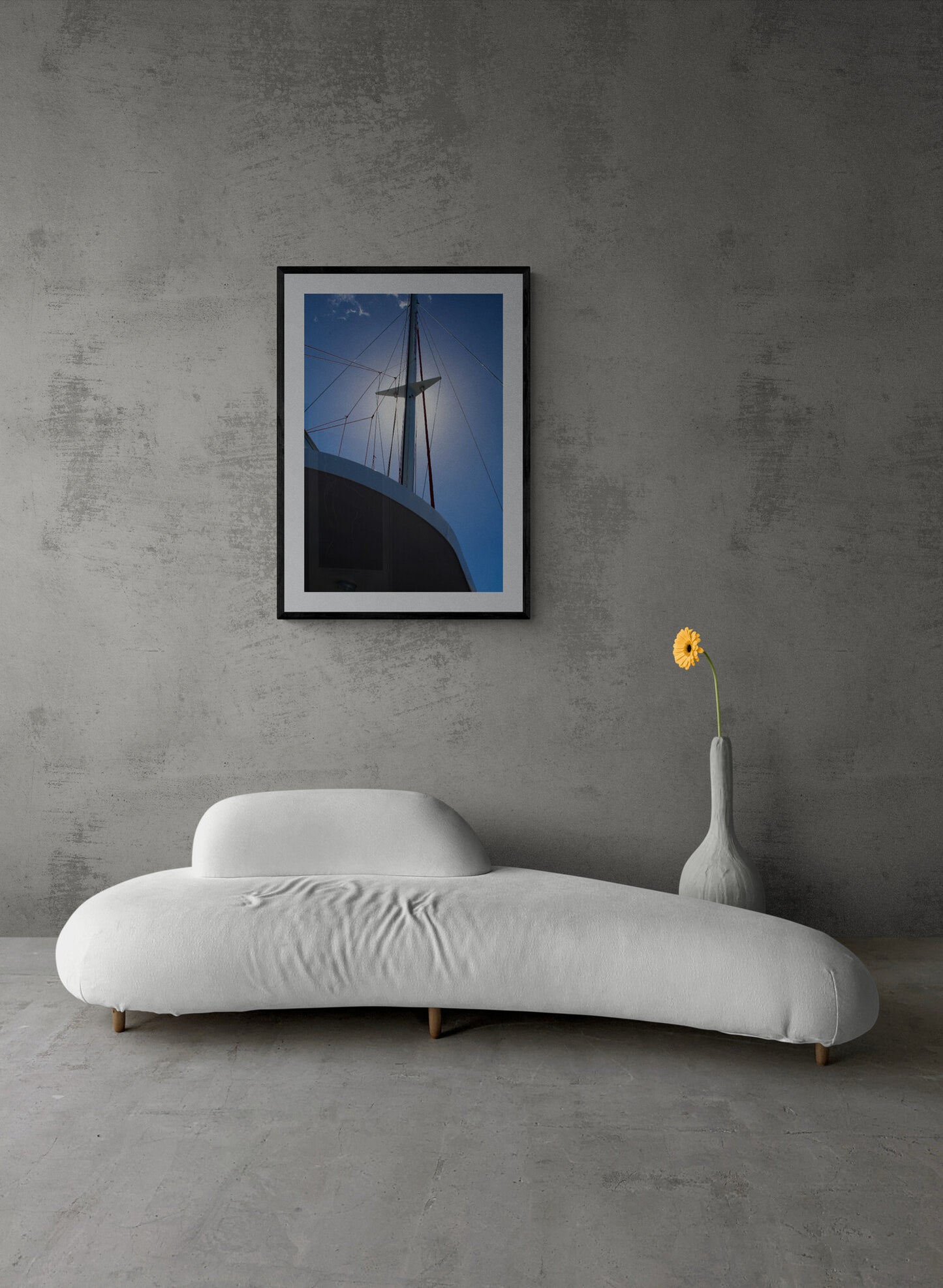 Modern white sofa in a room with a gray wall and a framed picture.
