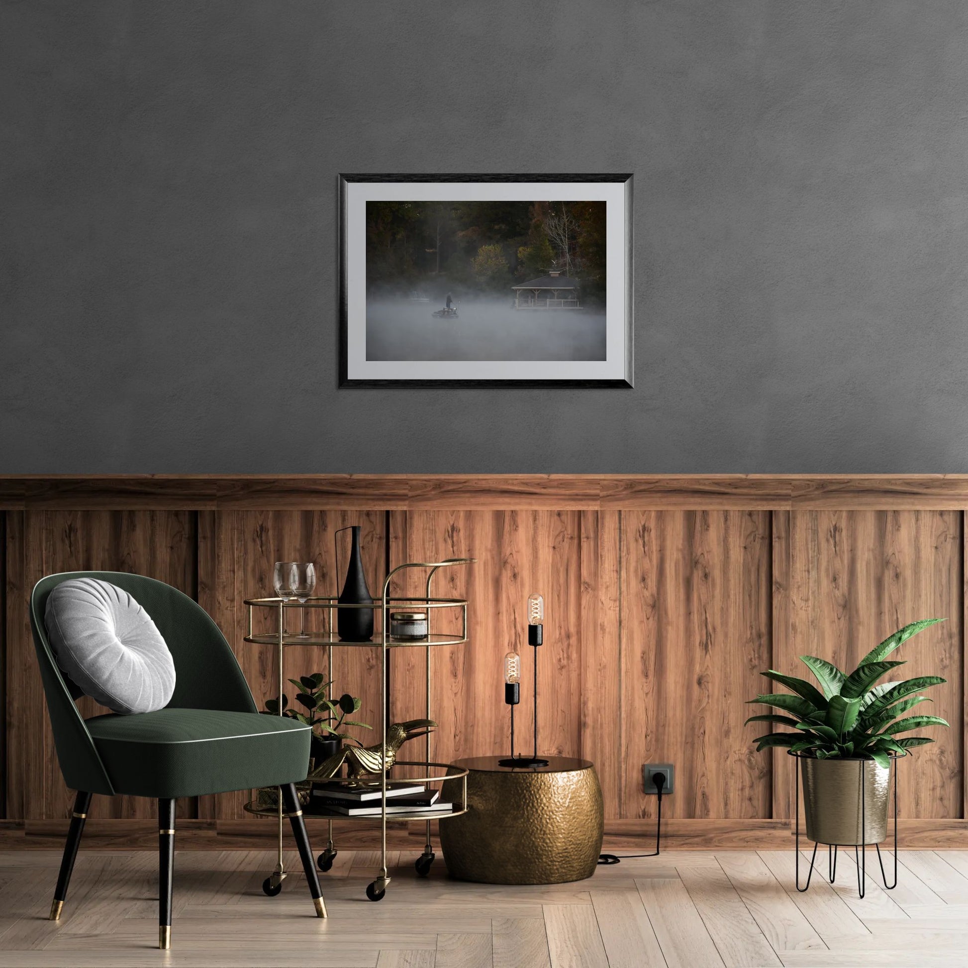 Person on a boat in a foggy lake with a gazebo in the background on a wall in  a modern interior with a green chair, wooden wall, and framed artwork.