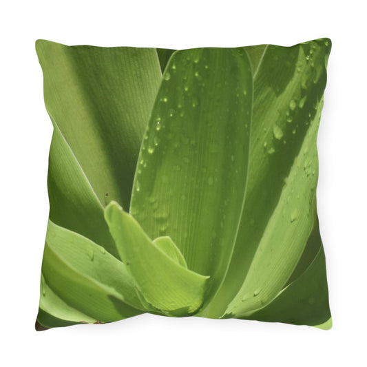 A square outdoor pillow with a photograph of green leaves printed on it, designed to be used for patio or outdoor space decoration.
