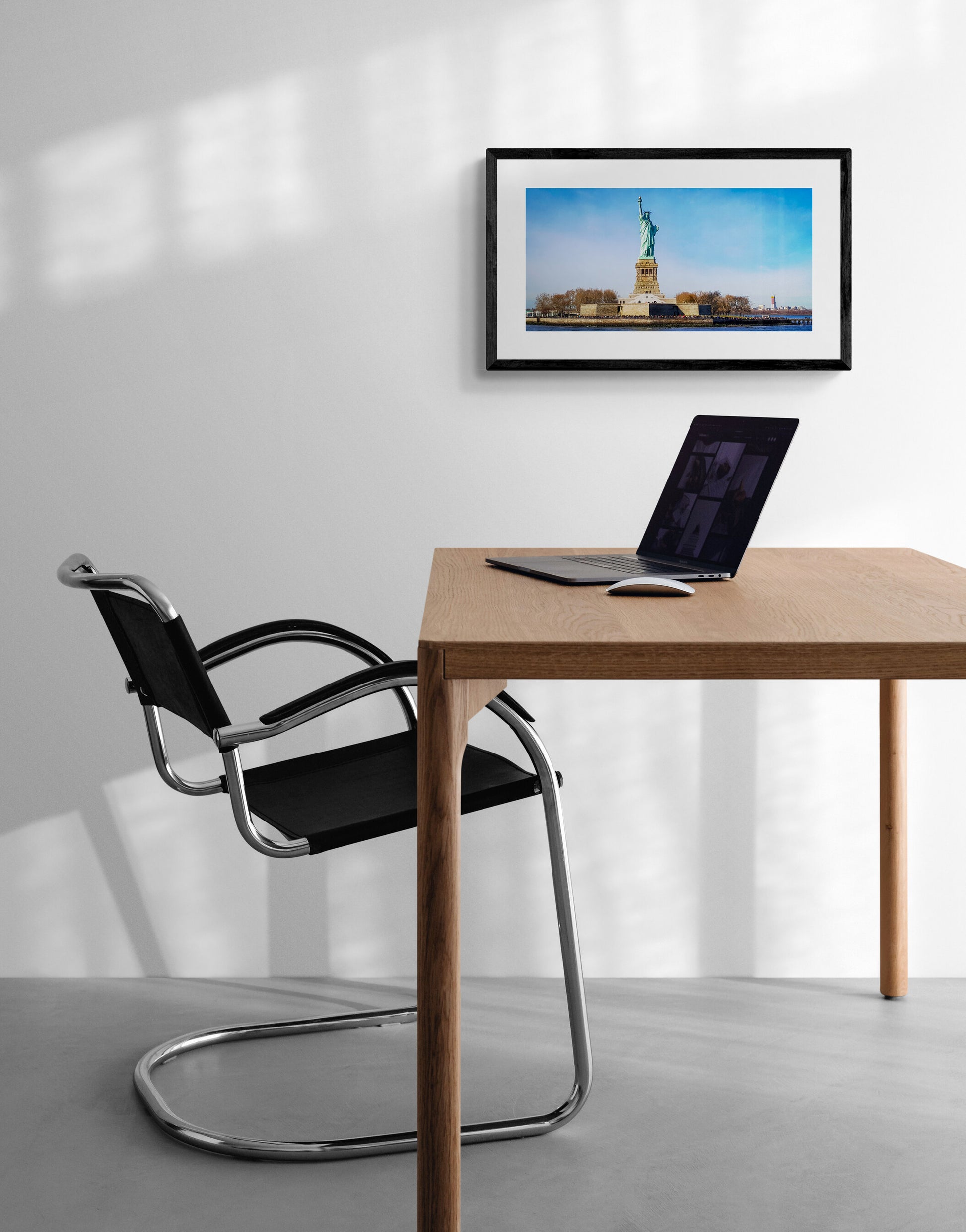 Modern office setup with a wooden desk, black chair, and framed picture of a cityscape.