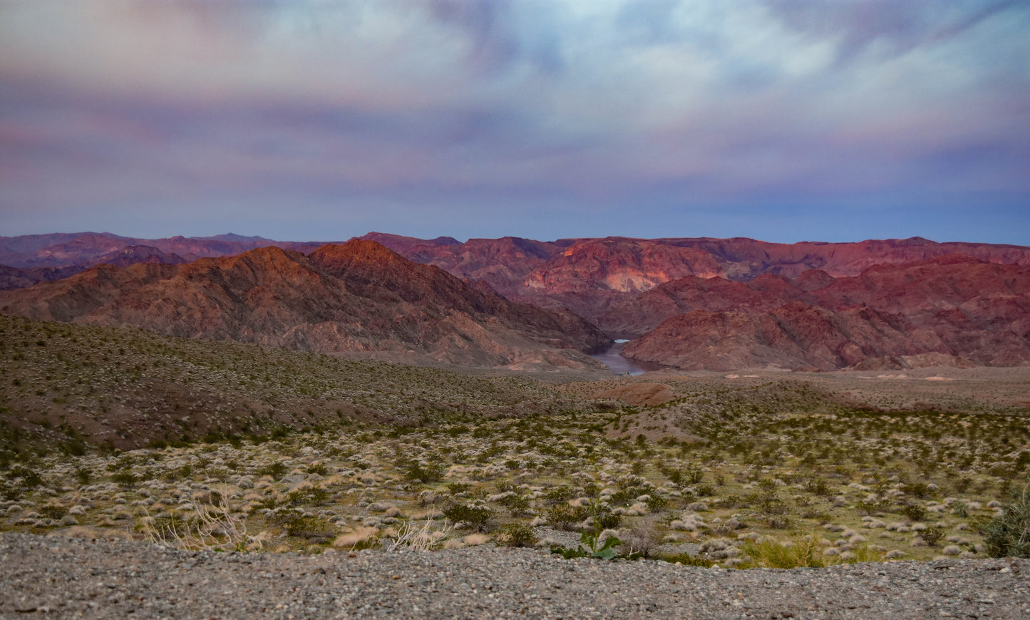 A landscape photograph featuring a sunrise over the Arizona desert, showcasing the mountains and a vast expanse of sand and cacti. Sunrise in Arizona