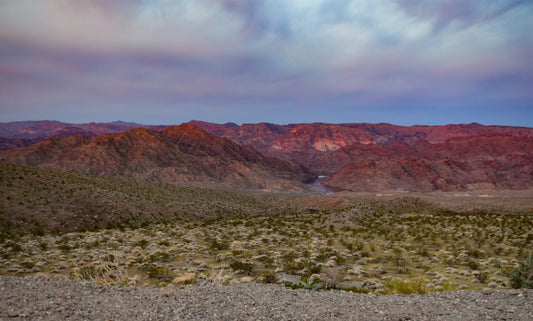 A landscape photograph featuring a sunrise over the Arizona desert, showcasing the mountains and a vast expanse of sand and cacti. Sunrise in Arizona