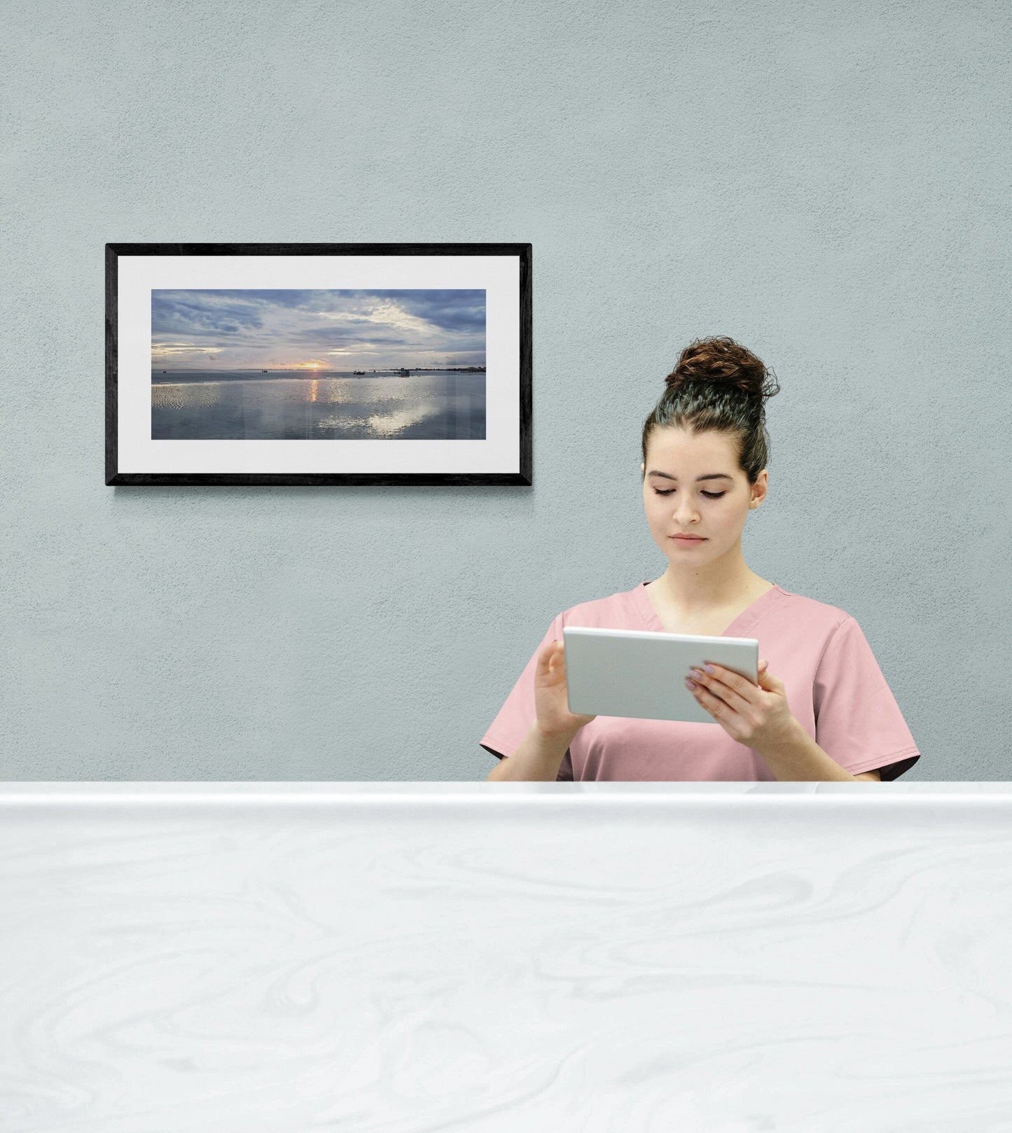 Woman using a tablet computer in a room with a framed picture on the wall. Sunset at Ft. Myers Beach, Original Photograph by Kim A. Bailey