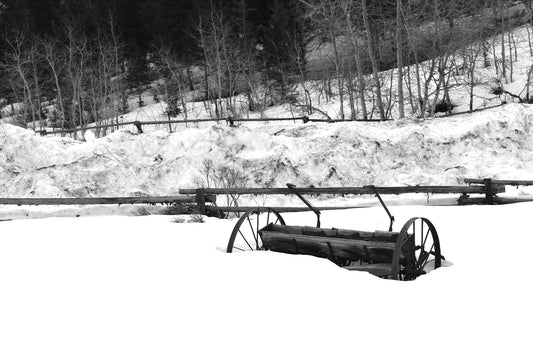 Black and white photograph of rustic wagon wheels in a snowy landscape, Jackson, Wyoming. Wagon Wheels in Snow Original Black and White Photograph by Kim A. Bailey