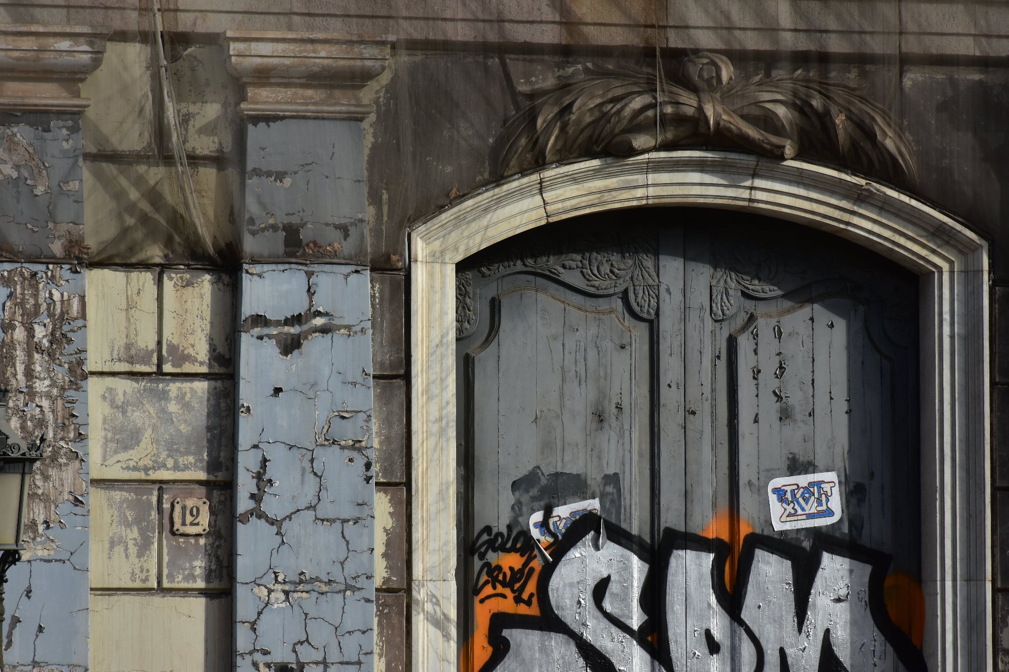 Worn-out door with graffiti and peeling paint on a textured wall. Original Photograph by Kim A. Bailey