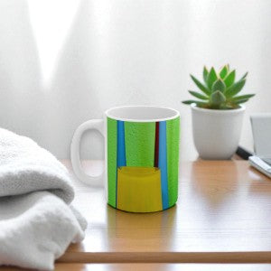 Colorful mug on a wooden surface with a plant and towel in the background
