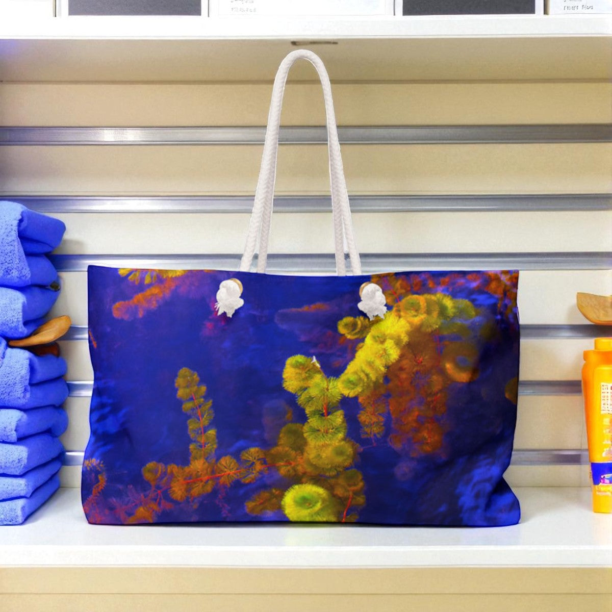 Colorful tote bag with floral design on a shelf Yellow and Purple Weekender Tote Bag by Kim A. Bailey